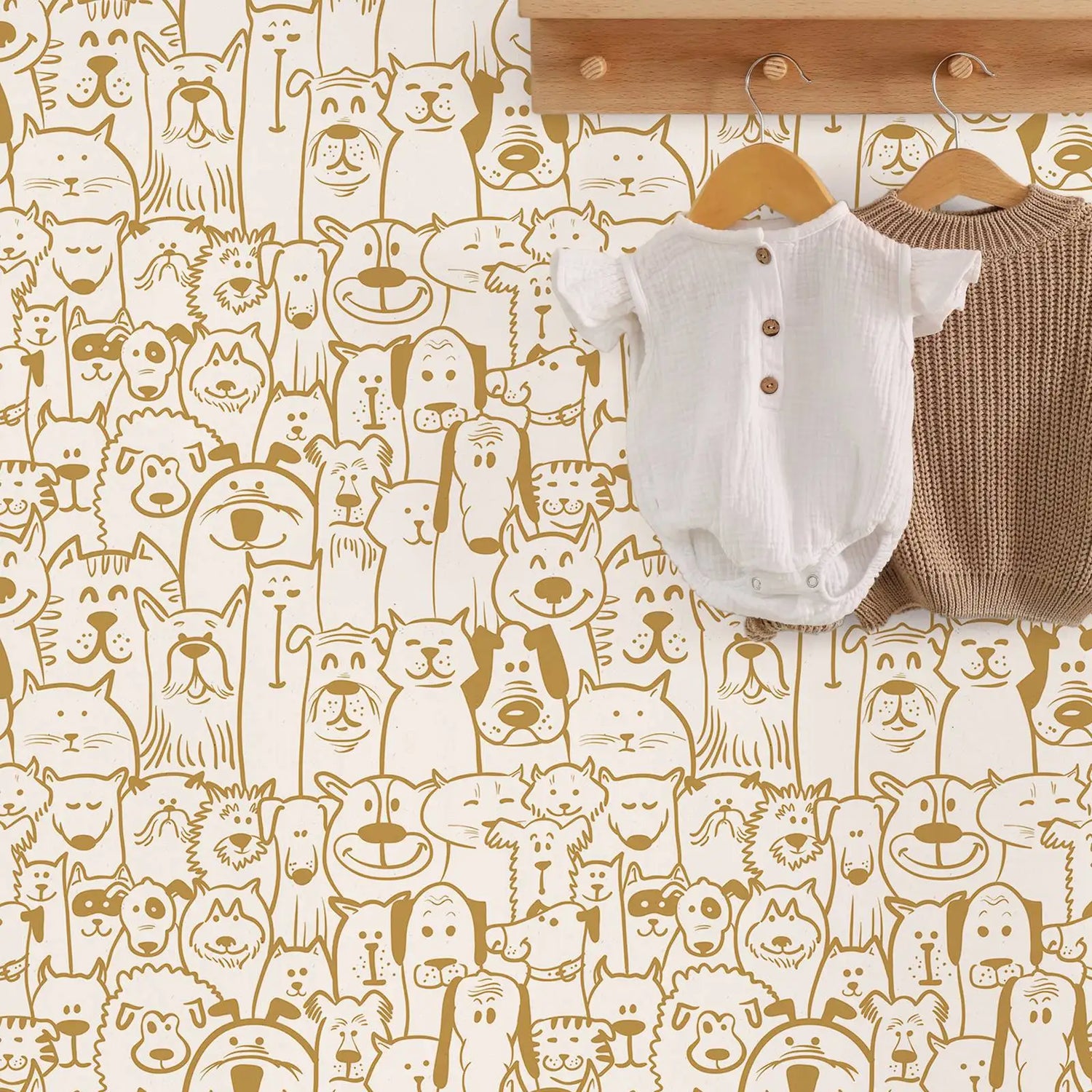 Baby onesie and sweater on hangers against a wallpaper with animal pattern
