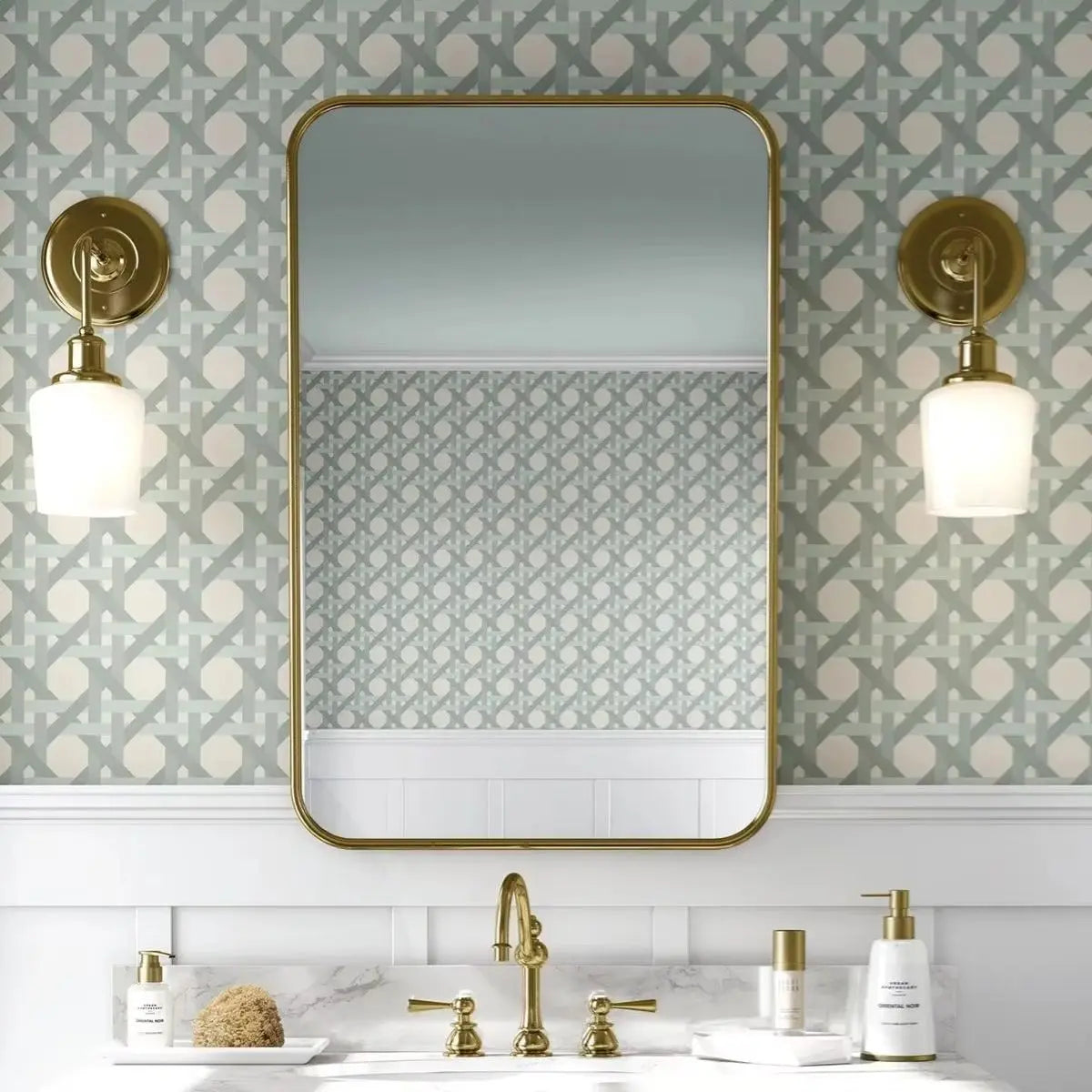 Bathroom with gold mirror and wall sconces against patterned wallpaper