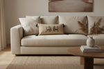 Beige sofa with decorative pillows and a wooden coffee table in a living room setting.