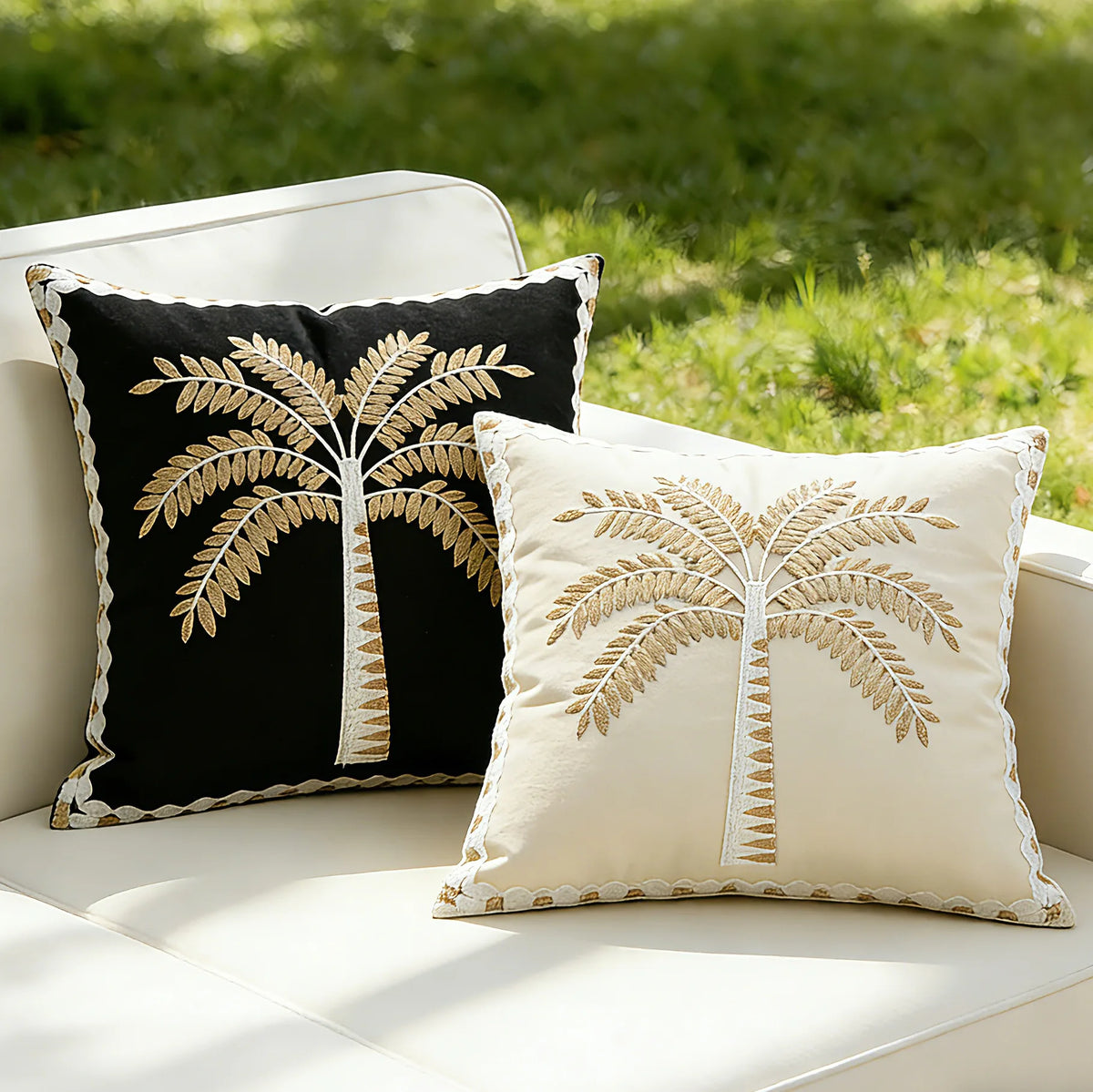 Two decorative pillows with palm tree designs on a white outdoor sofa.