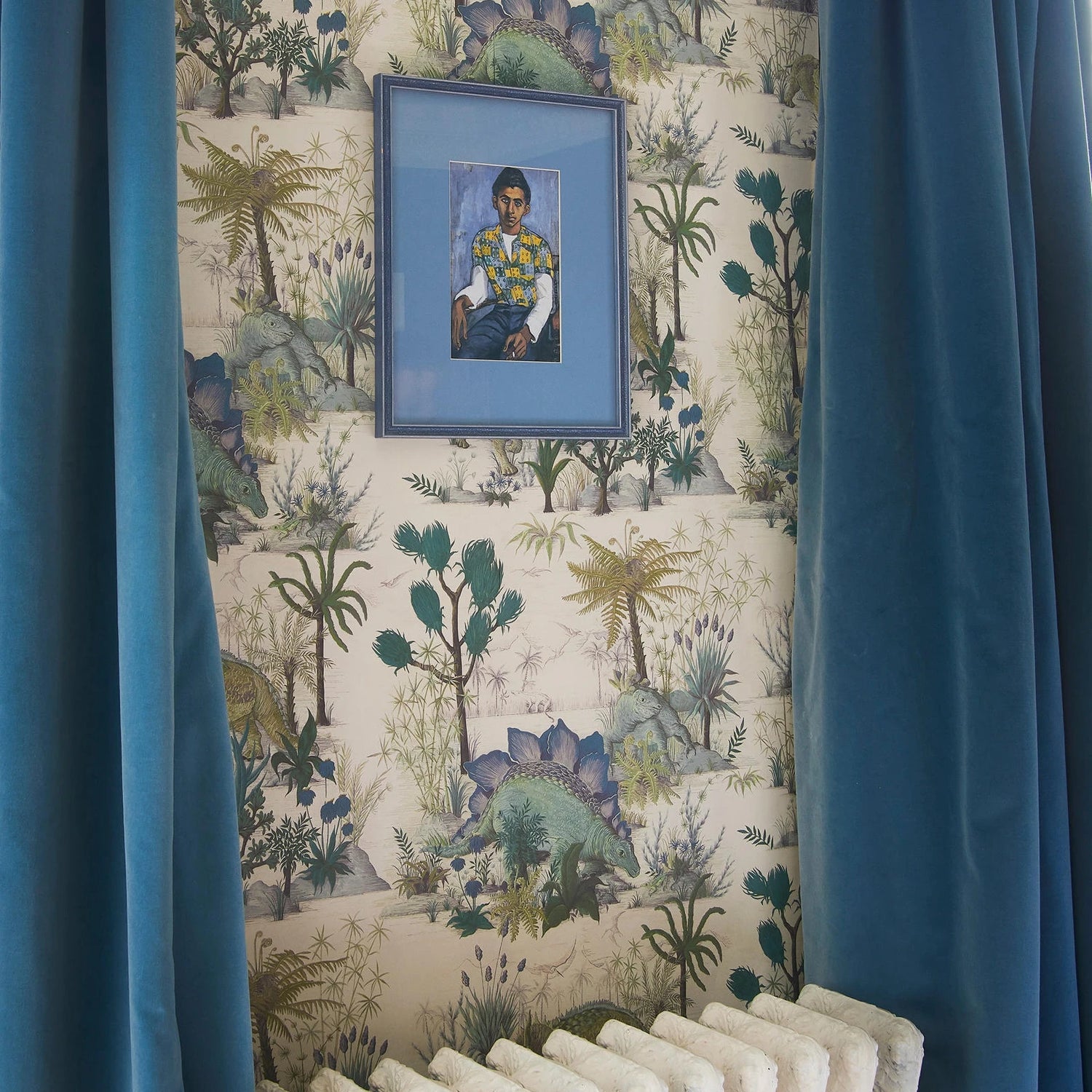 Framed portrait on a wall with decorative wallpaper and blue curtains