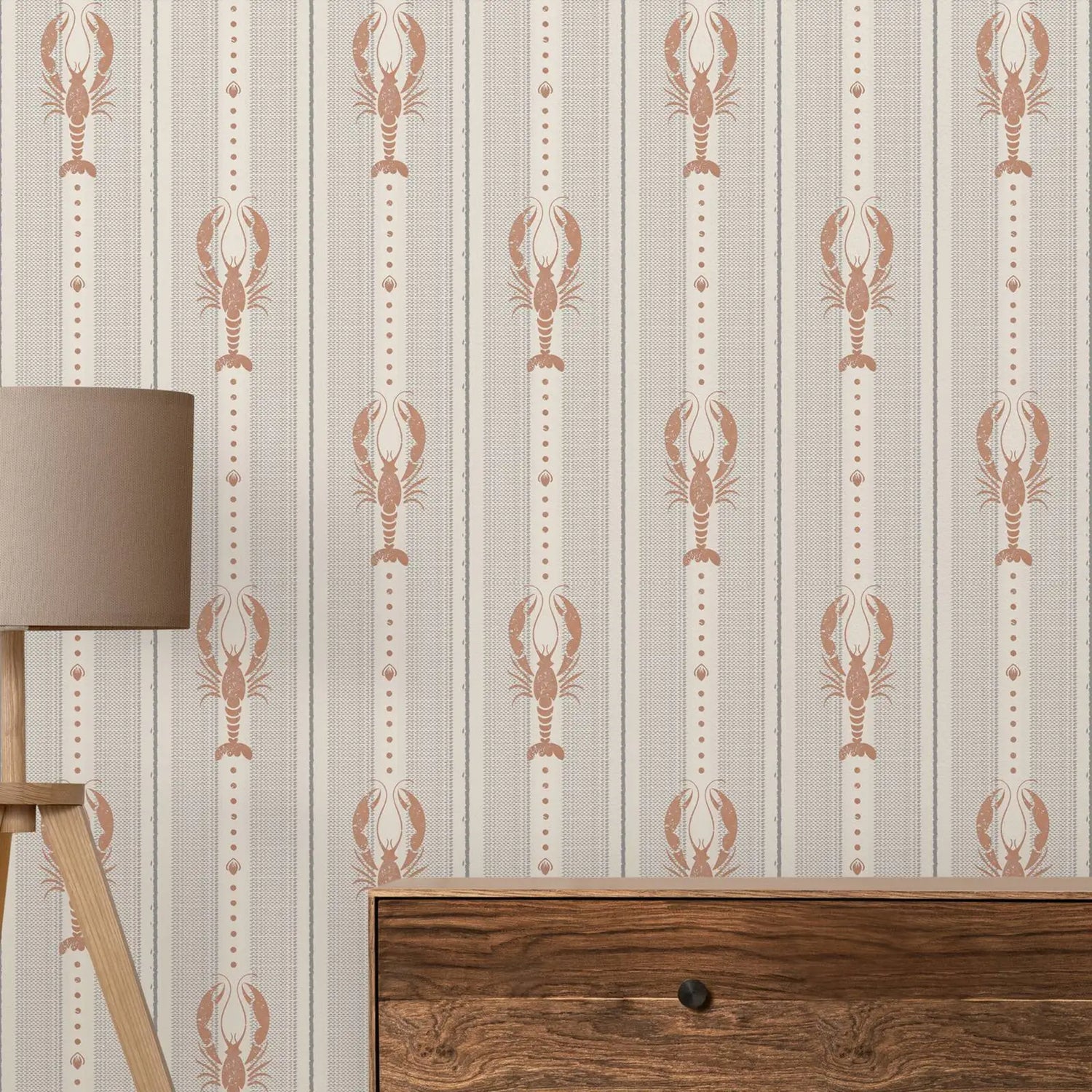 Wallpaper with lobster pattern on a wall next to a wooden cabinet and lamp.