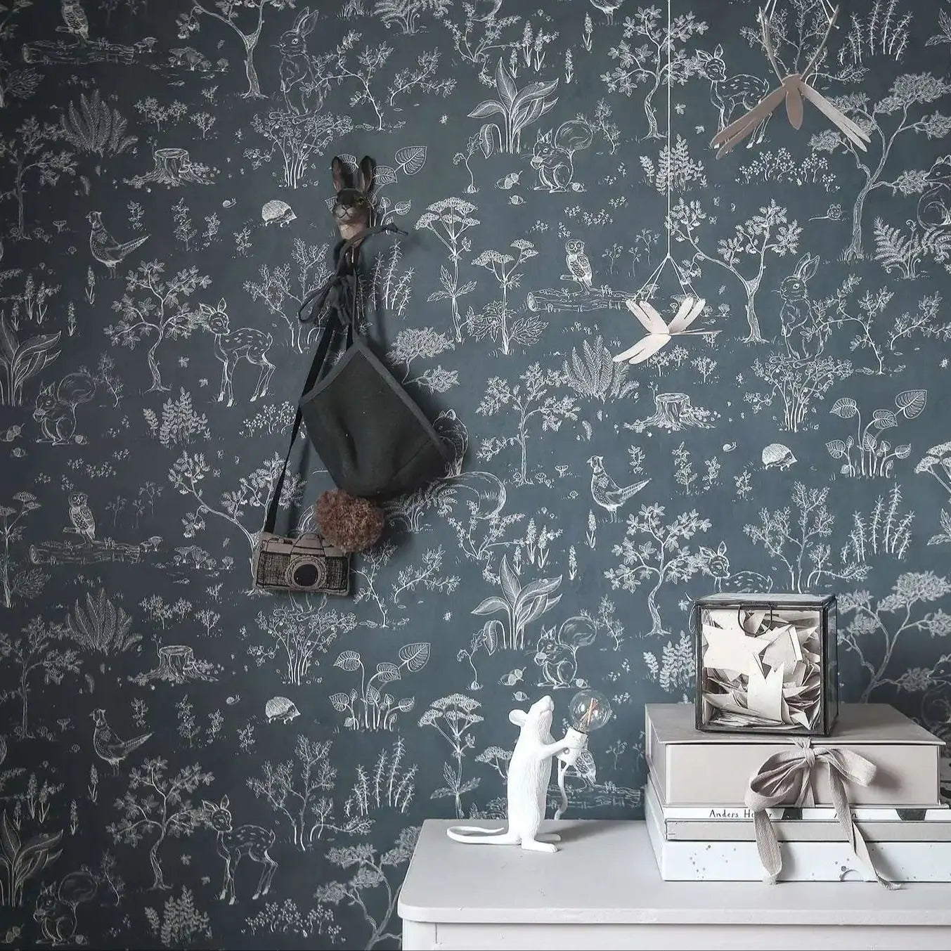 Wallpaper with nature-themed design and decorative items on a shelf.