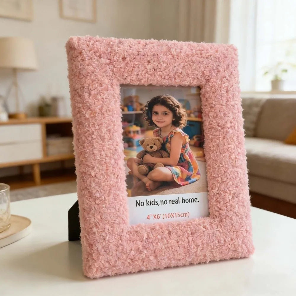 Pink textured picture frame with a photo of a child holding a teddy bear, placed on a surface in a room.