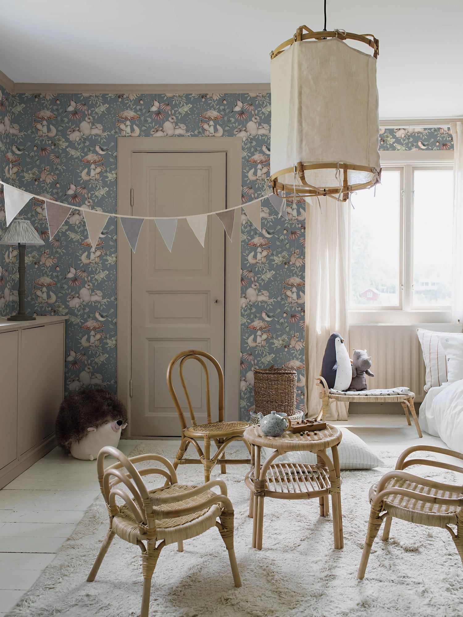 Children's room with floral wallpaper, wicker furniture, and a small table with toys.