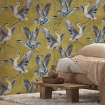 Wallpaper with bird pattern on a wall above a bed with a wooden nightstand.
