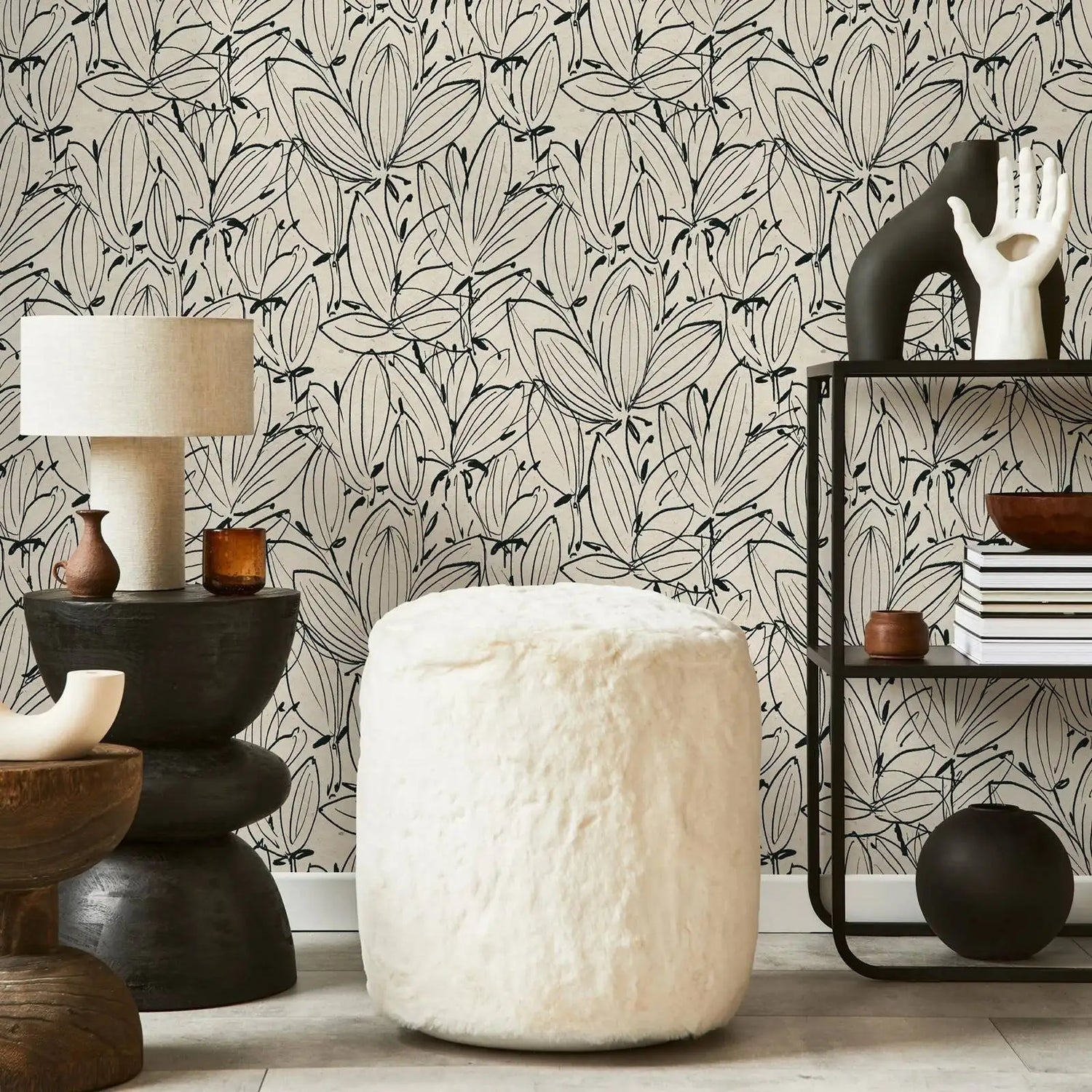 Living room with textured white ottoman, leaf-patterned wallpaper, and decorative items.