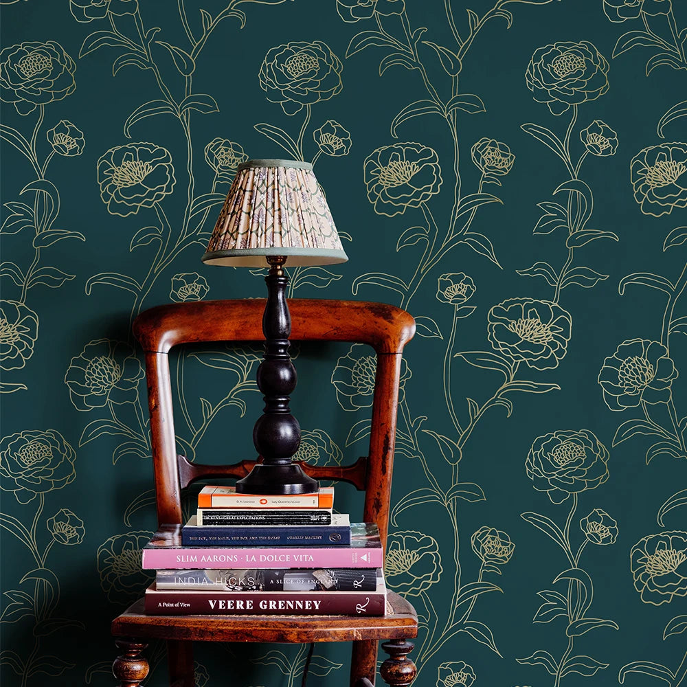 Wooden chair with a lamp and books against a floral-patterned wall.