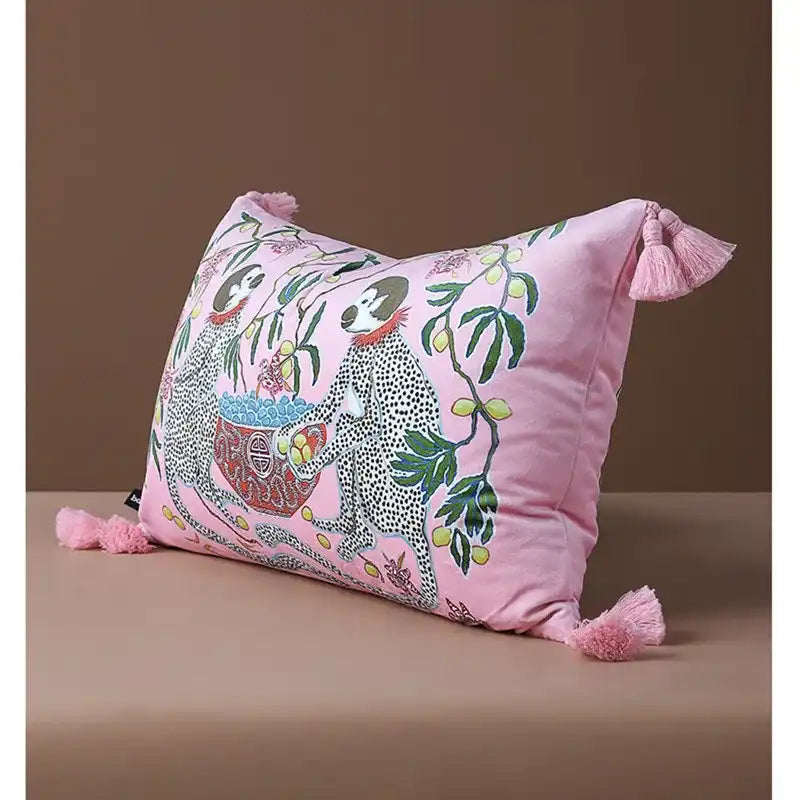 Retro monkey charm throw pillow with vibrant pink fabric and playful tassels, featuring whimsical monkey illustrations and botanical elements, perfect for adding a pop of color to any living space.