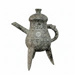 Bronze teapot with intricate designs on a black background