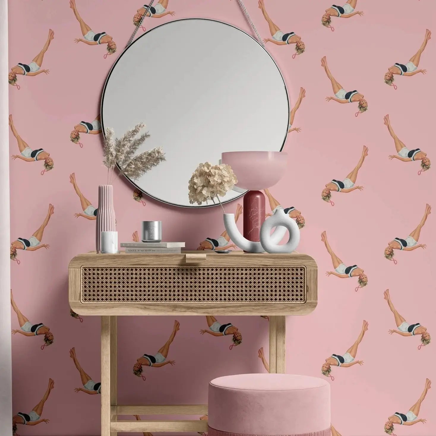 Pink vanity table with mirror and decorative items against a pink wallpaper with swimmer pattern