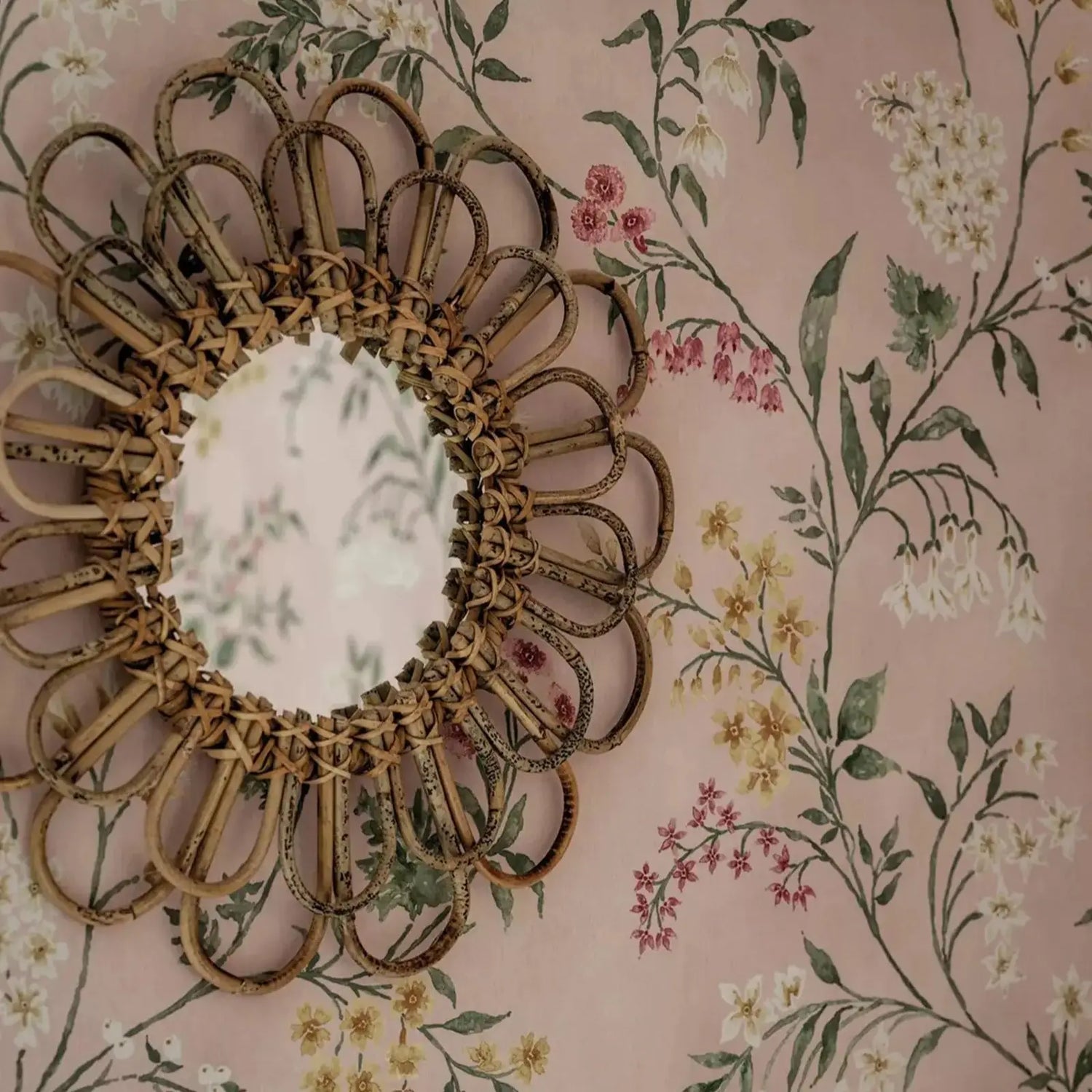 Decorative mirror with floral design on a floral wallpaper background