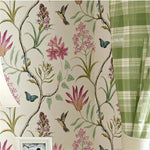 Floral wallpaper with pink flowers and green leaves, next to a green plaid fabric.