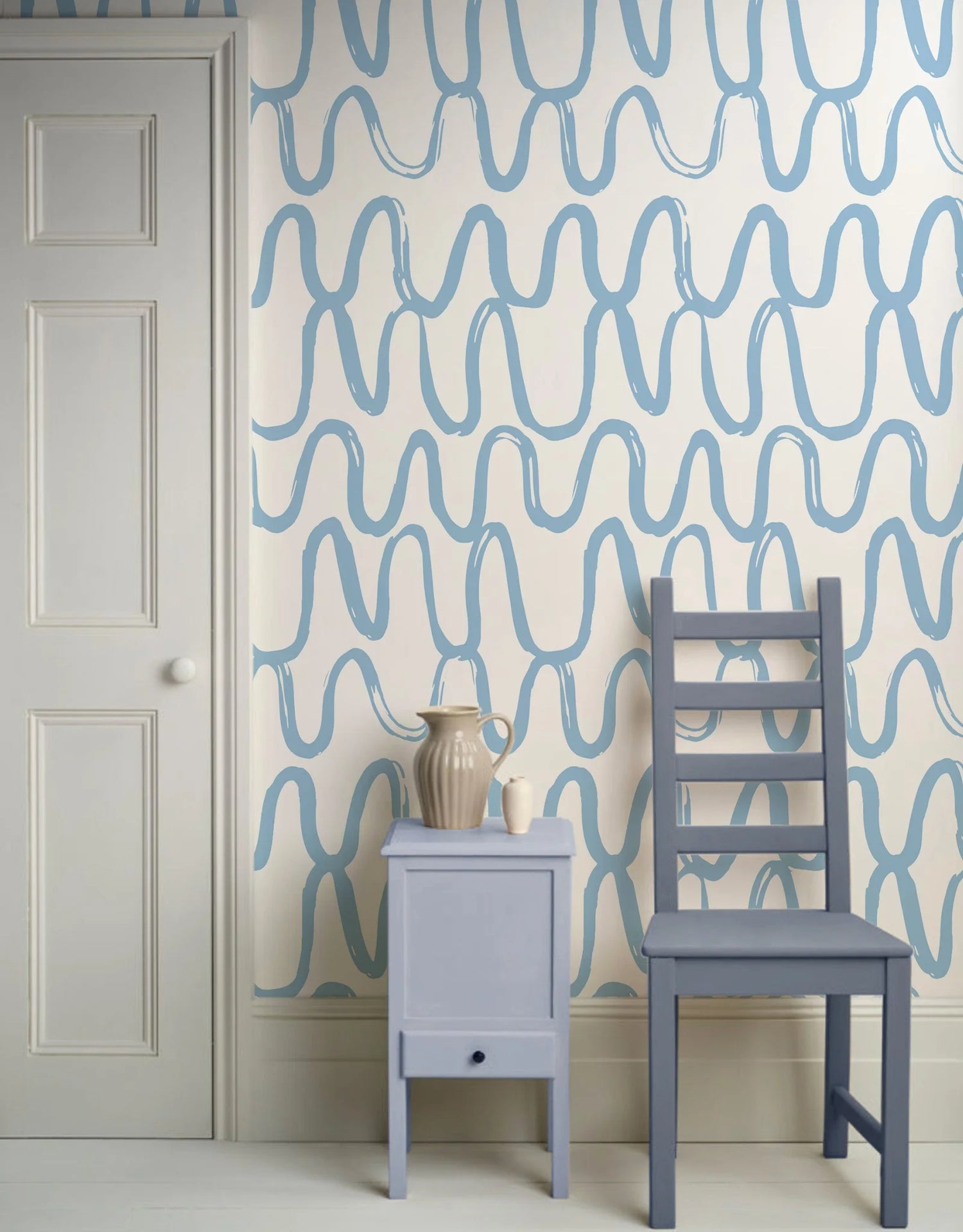 Gray chair and cabinet against a wall with blue wavy pattern