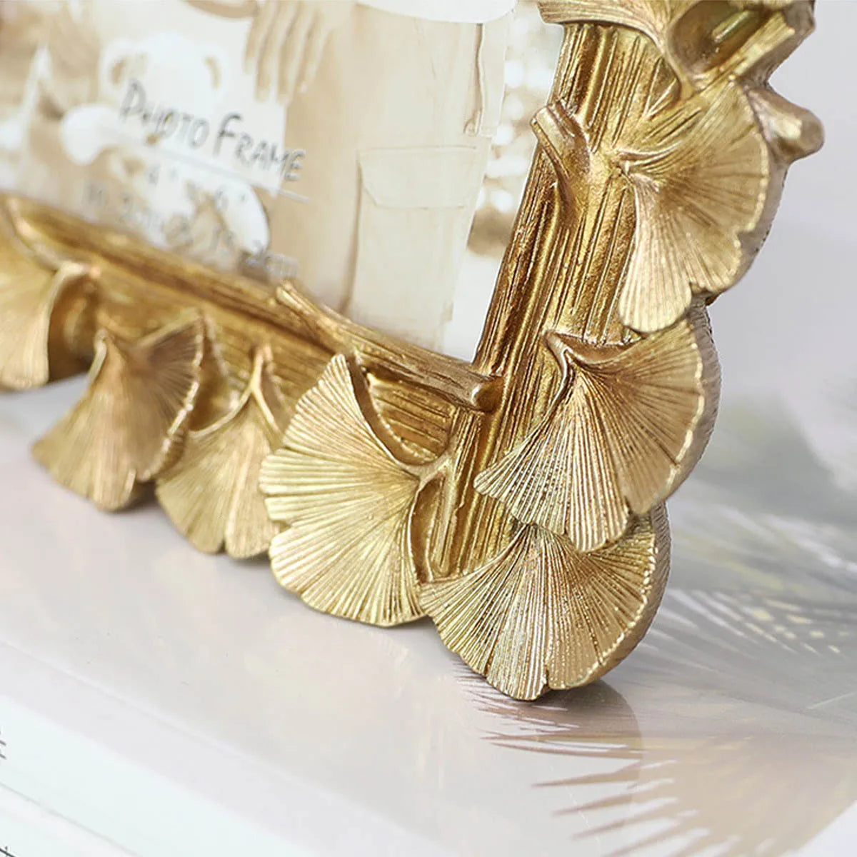Gold decorative frame with leaf design on a white surface