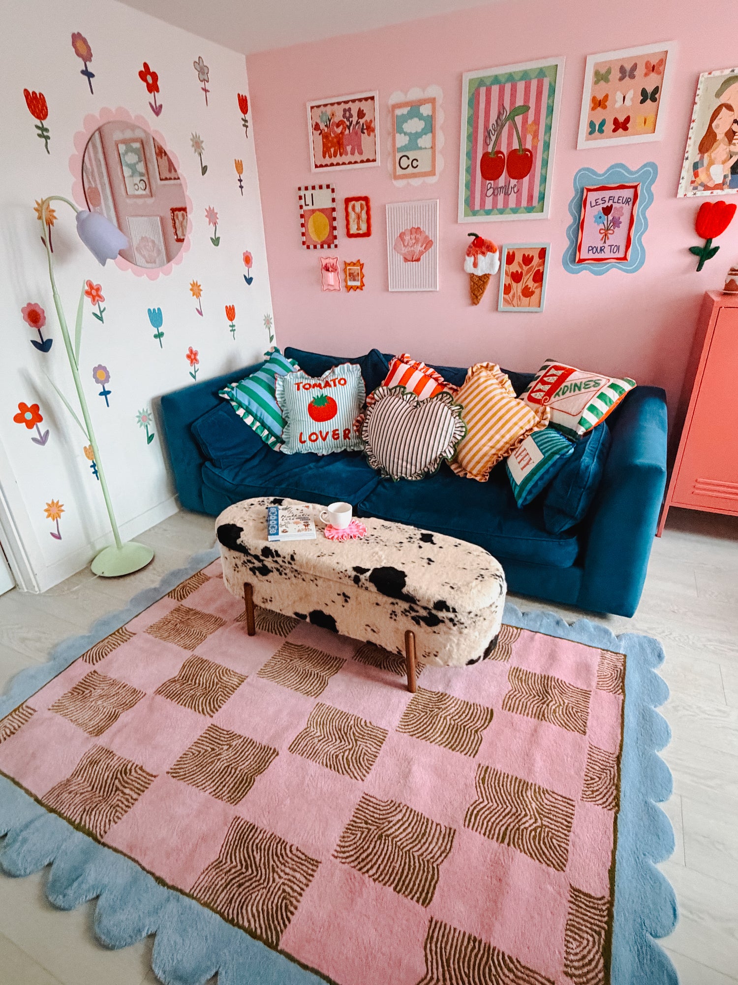 Children's room with a blue sofa, colorful cushions, and a checkered pink and brown rug.
