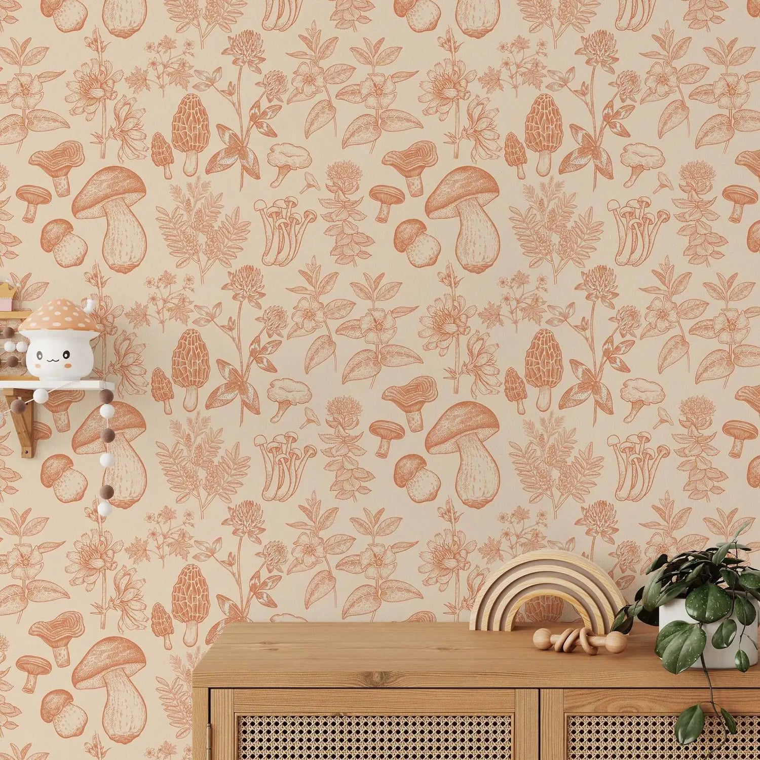 Wallpaper with mushroom and floral pattern in orange on a beige background, with a wooden cabinet and decorative items below.