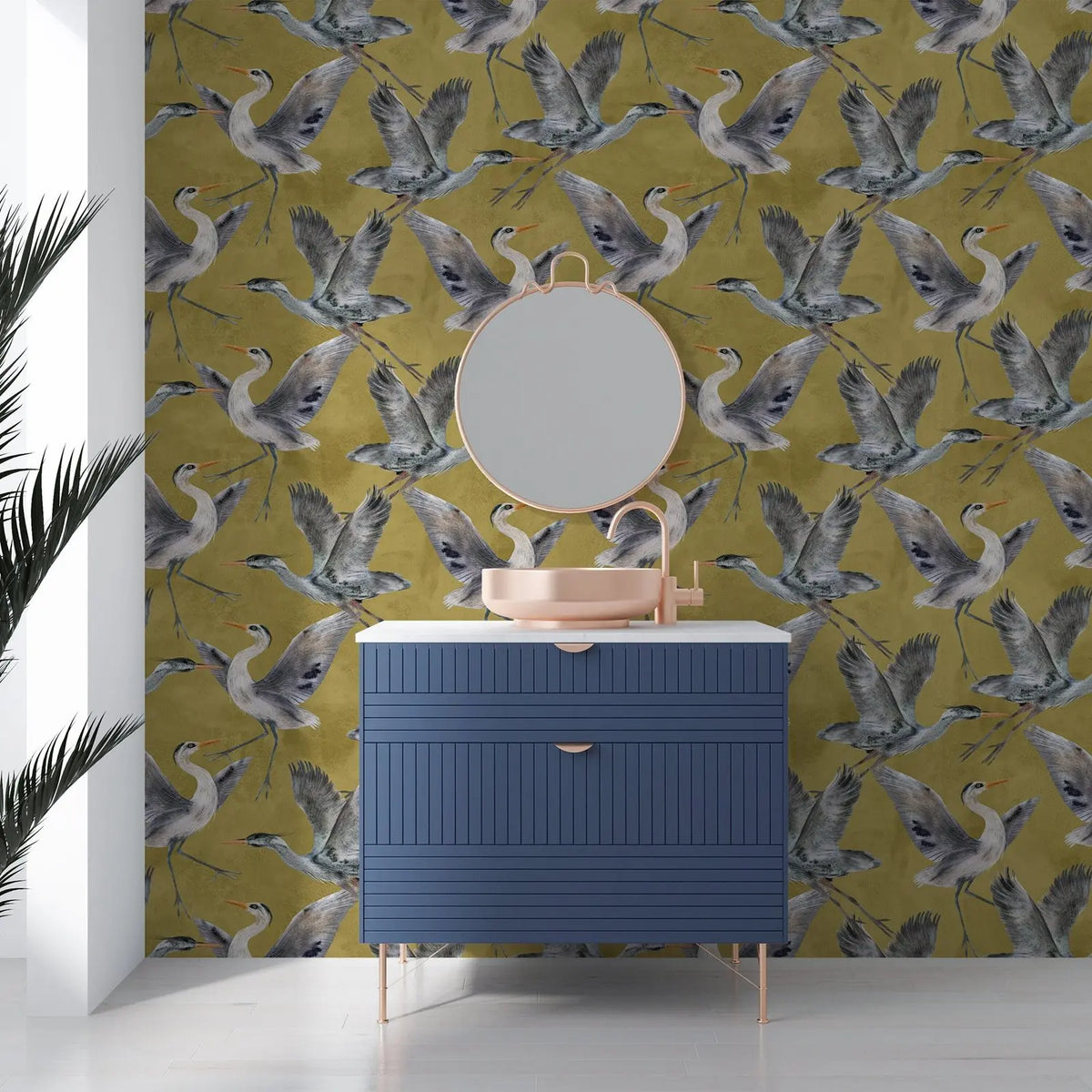 Bathroom with blue cabinet, round mirror, and green wallpaper with bird pattern