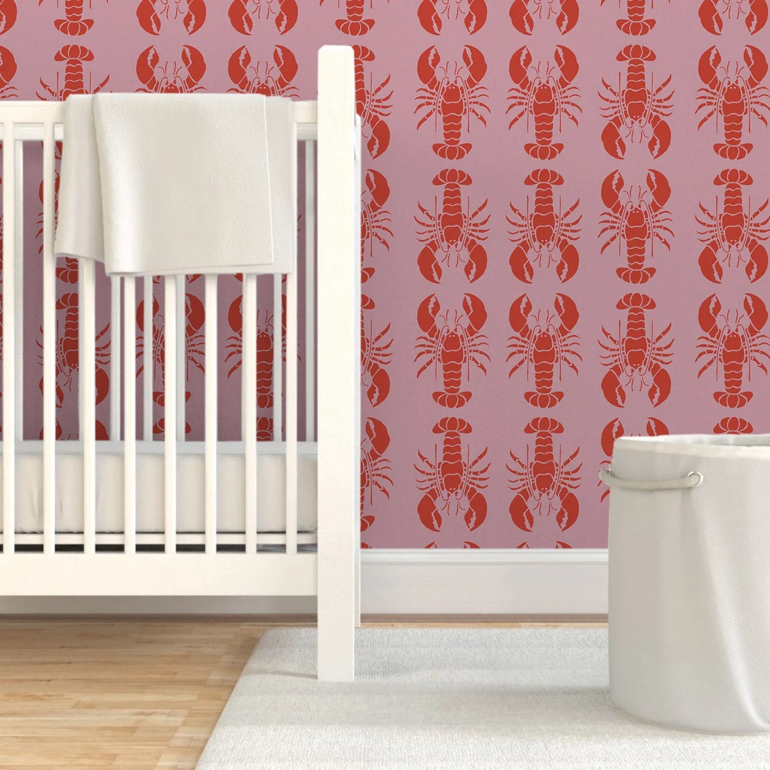 Nursery room with white crib and red lobster pattern on pink walls.