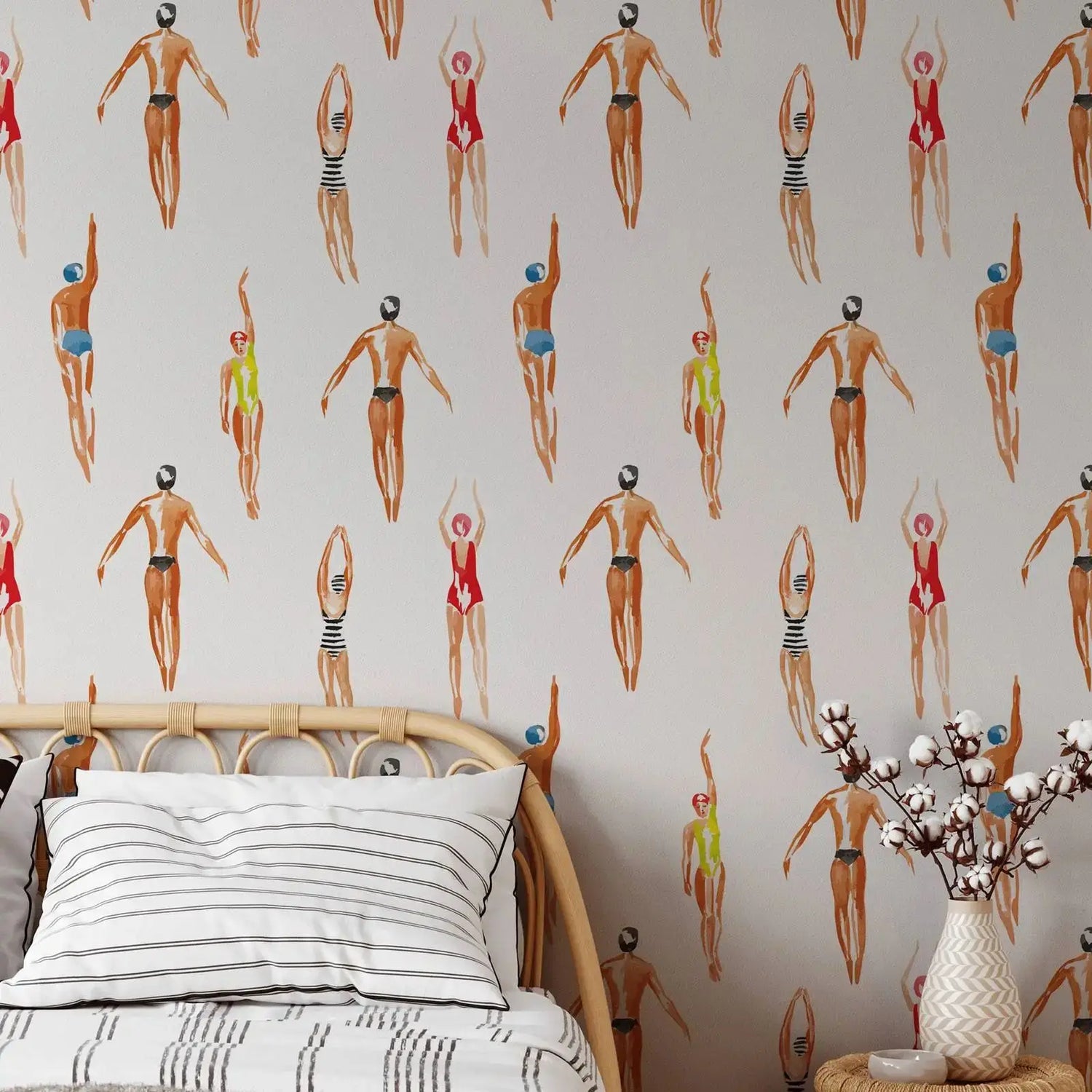 Bedroom with a wallpaper featuring illustrated figures in swimsuits, a bed with striped bedding, and a vase with cotton branches.