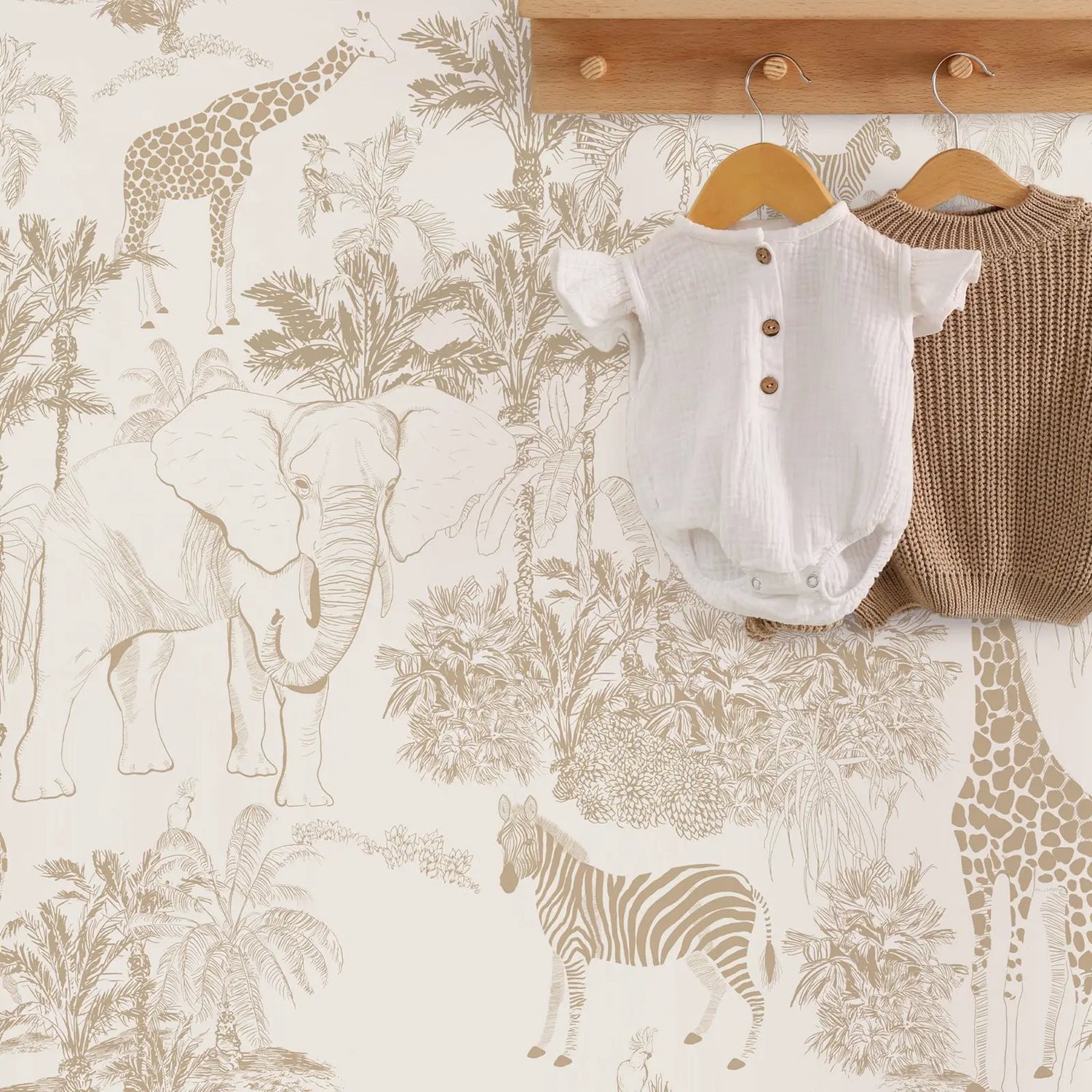 Baby clothes on hangers against a wallpaper with animal patterns