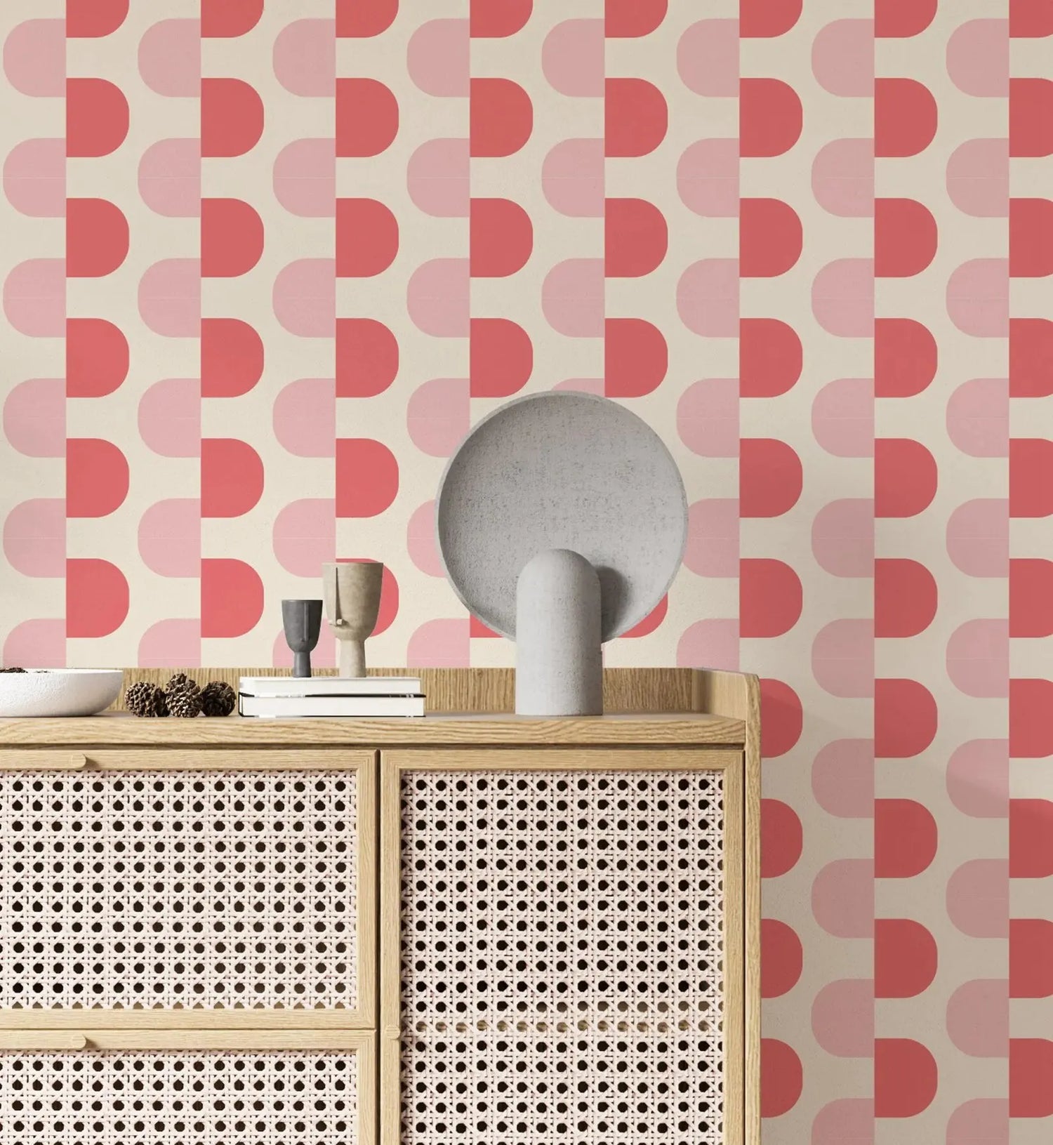 Decorative wallpaper with pink geometric pattern, wooden cabinet with wicker doors, and decorative items.