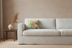 An olive green velvet loveseat sofa with a colorful tropical print accent pillow, styled in a room setting with a side table and vase.