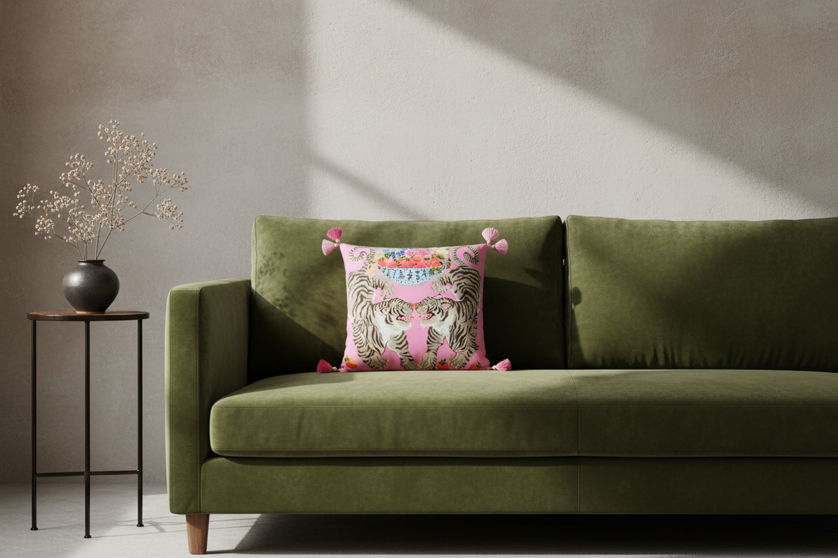 A pink decorative throw pillow with a tiger print and colorful floral details, styled on a white slipcovered sofa in a living room setting.