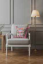A pink decorative throw pillow with a tiger print and colorful floral details, styled on a white slipcovered sofa in a living room setting.