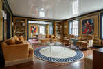 Luxurious living room with yellow sofas, a round rug, and decorative elements.