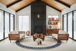 Modern living room with high ceilings, large windows, and a dog sitting on a round rug.