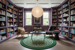 Library with bookshelves, chairs, and a green round rug.