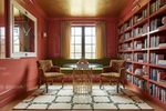 Cozy room with red walls, handmade rug, bookshelves, and a round table with chairs.