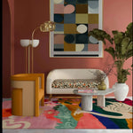 A vibrant, hand tufted area rug featuring abstract designs and bold colors, perfect for a large living room or office. The wool rug adds a splash of creativity beneath a modern sofa and stylish furniture, enhancing the living room's decor with its artistic flair.