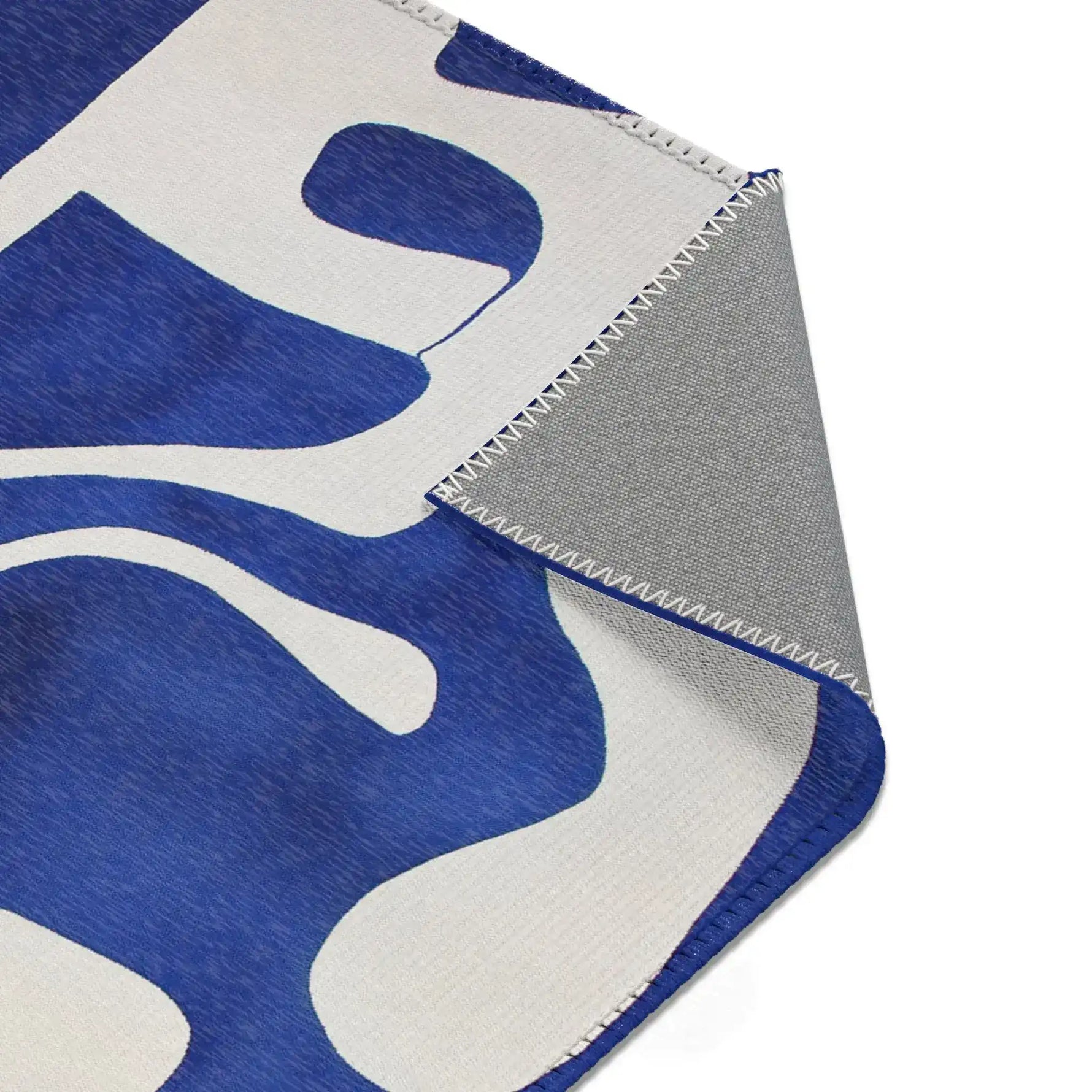 Abstract Blue and White Geometric Rug corner detail folded back revealing cobalt blue and white front and grey non-slip backing