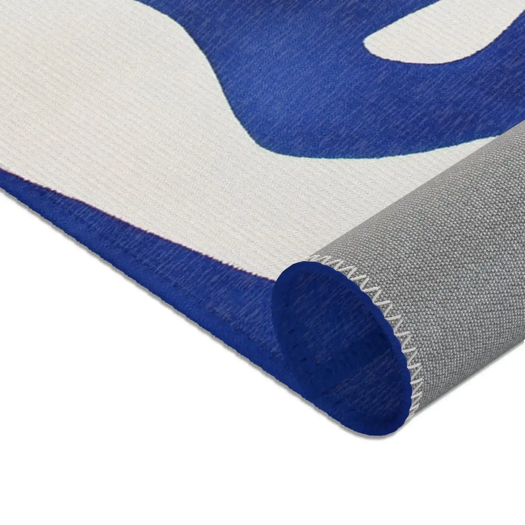Abstract Blue and White Geometric Rug corner curl view, cobalt blue and white surface with grey non-slip backing and rolled edge