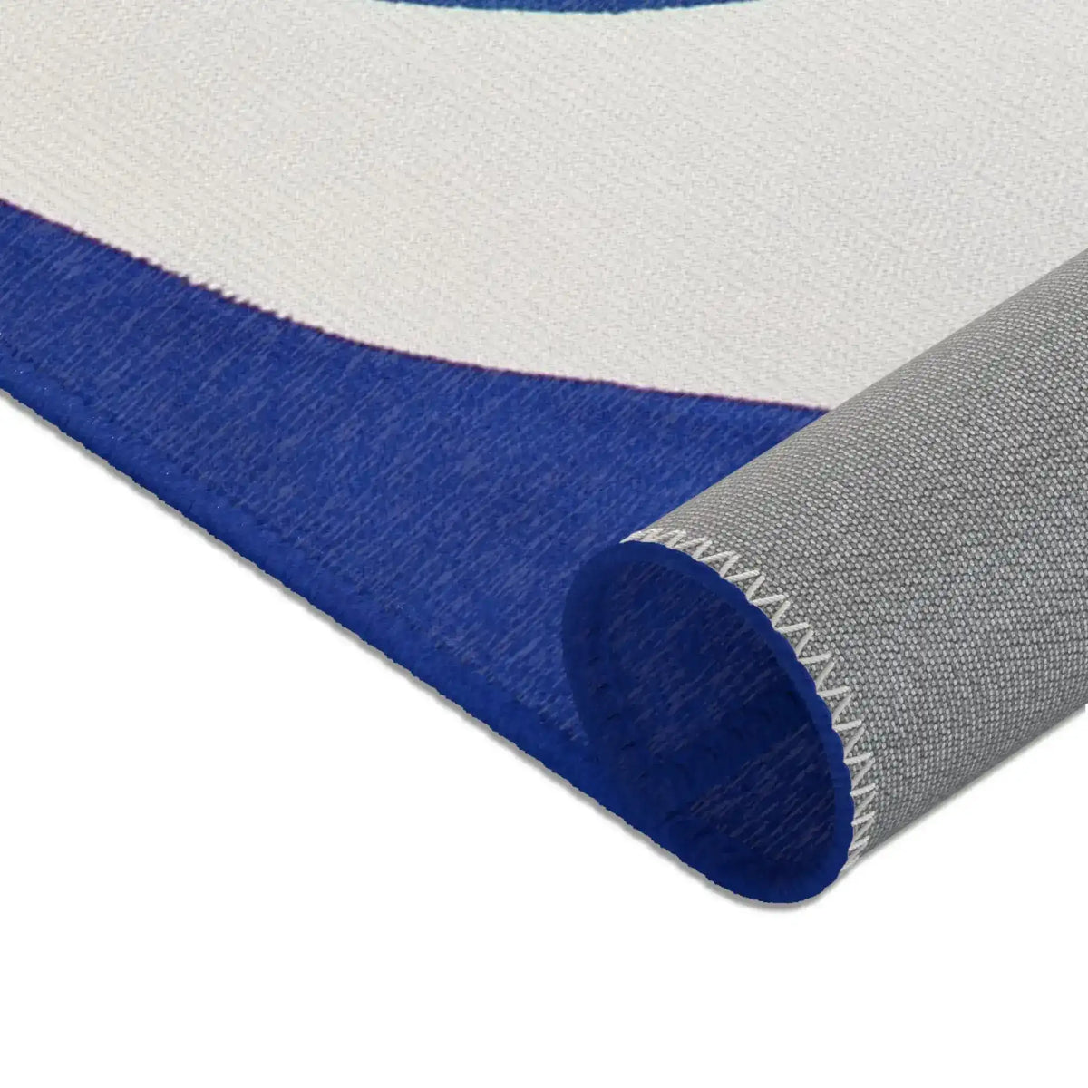 Abstract Blue and White Geometric Rug rolled corner showing cobalt blue and ivory printed face with grey non-slip backing and white zigzag overlock stitching