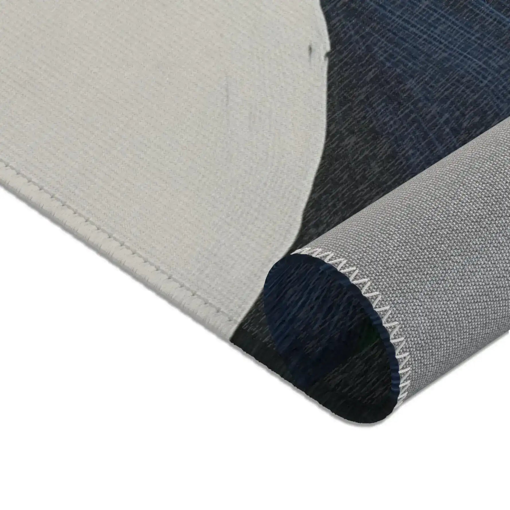Abstract Duality Flowing Contrast Rug rolled corner close-up with white backing and dark charcoal blue print surface and overlock edge — material detail