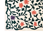 A stylish hand-tufted wool area rug featuring an abstract floral meadow design. The rug showcases vibrant green vines with red and purple flowers set against a light background, adding a touch of elegance and nature-inspired charm to any room.