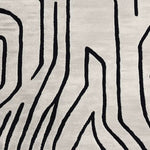 Top view of a contemporary rug showcasing an abstract design with bold black lines on a soft, cream wool surface. Perfect for enhancing living room spaces, this 8x10 area rug combines modern style with cozy comfort, ideal for those seeking stylish living room area rugs.