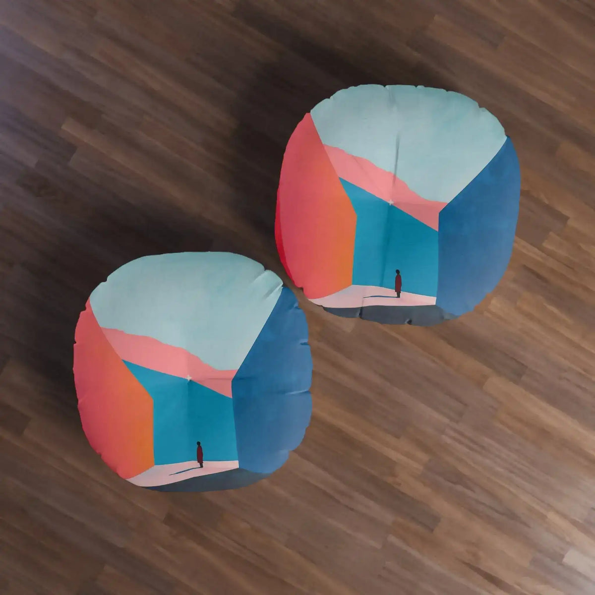 Pair of Abstract Geometric Color Block Floor Pillows in coral and navy blue on dark wood floor, top-down overhead view