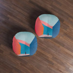 Two Abstract Geometric Color Block Floor Pillows on dark wood floor, overhead pair view with orange and blue design