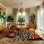 abstract odyssey hand tufted viscose rug in a botanical dining room with live-edge wood table, rattan pendant and tropical plants