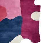 This vibrant area rug showcases an abstract design with bold color blocks in pink, blue, and maroon, perfect for adding a contemporary touch to any living room. Hand tufted from wool, it's a stylish choice for those seeking unique rugs for living room decor.