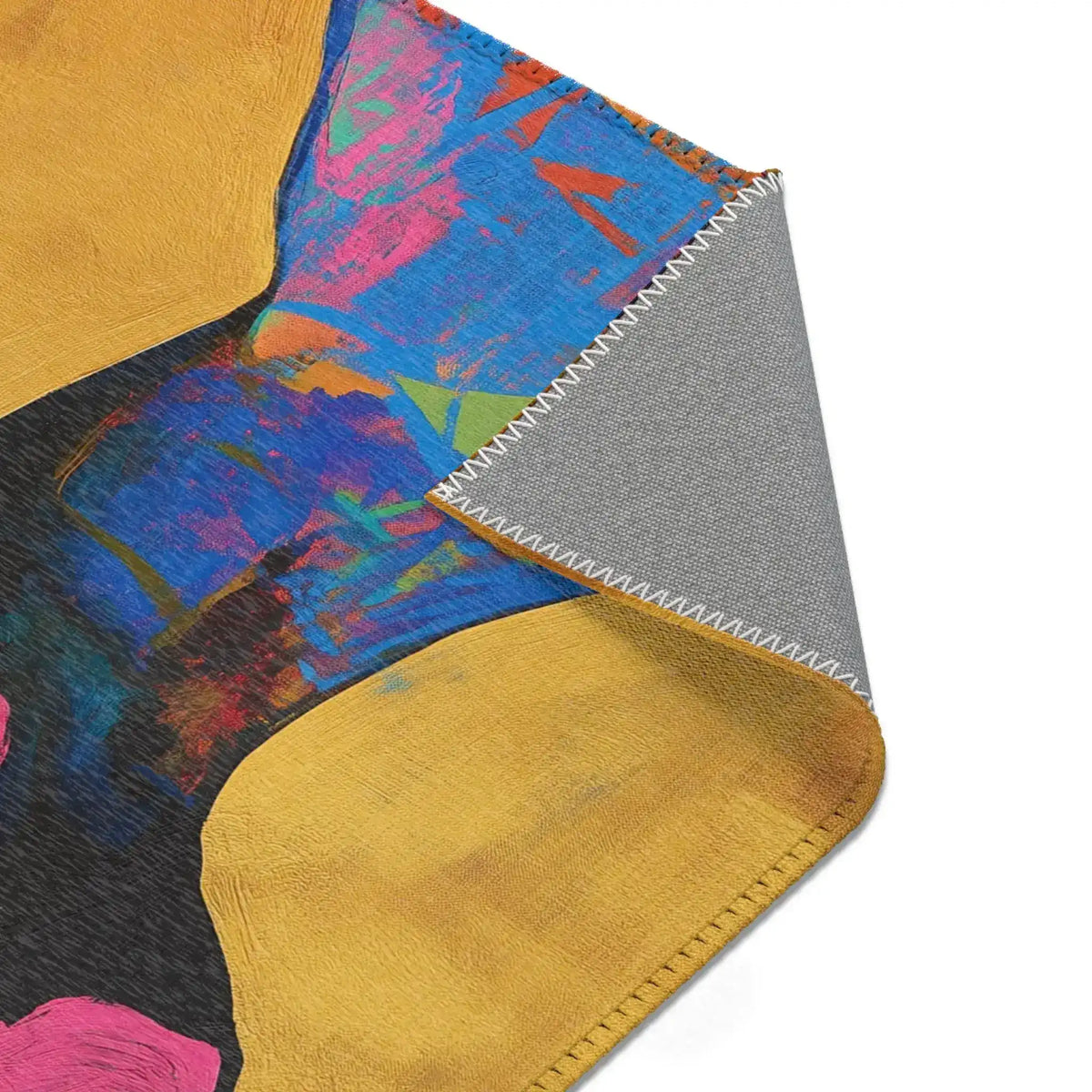 Folded corner of Abstract Silhouette Rug showing golden and deep blue abstract silhouette design on face, colorful neck pattern, grey non-slip backing exposed