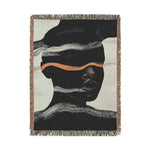 Portrait-cropped woven blanket with dark figure, white static wave bands and copper stripe accent on off-white ground, fringe border