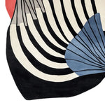 Close-up view of the Aerodynamic Pulse Hand Tufted Rug showcasing its contemporary design. This area rug features bold, curved black and white stripes with a striking blue and red abstract pattern, perfect for large living rooms. Crafted from high-quality wool, this rug enhances any living room with its modern flair.