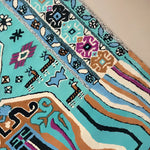 Close-up of the Alaia Persian Turquoise Melting Area Rug showcasing its intricate patterns and vibrant colors. This large wool rug is perfect for adding a stylish touch to your living room or office.