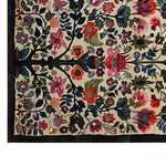 A vibrant hand-tufted wool area rug showcasing an artistic floral design. The rug features a lively array of colorful flowers and leaves, creating a striking pattern against a neutral background, perfect for adding a touch of elegance to any living space.