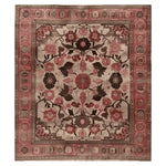 A richly detailed Arcadian Grandeur Knotted Wool Area Rug featuring an intricate floral pattern in shades of red, pink, and brown, set against a beige background. The rug showcases a traditional design with a decorative border, highlighting its handcrafted elegance.